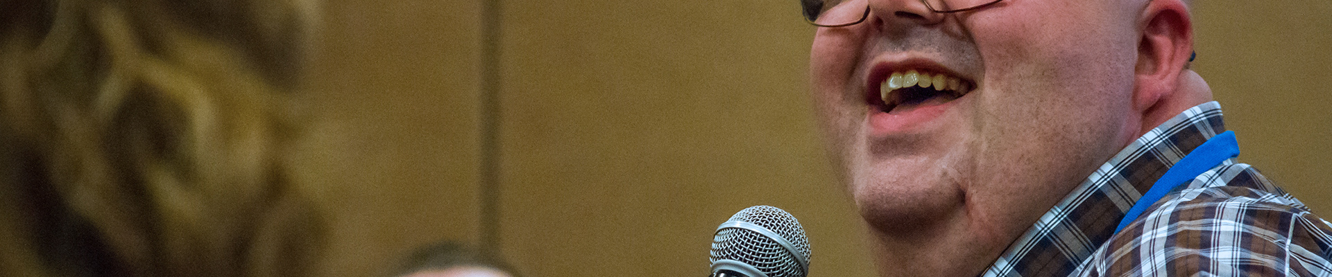 Man smiling while speaking into a microphone