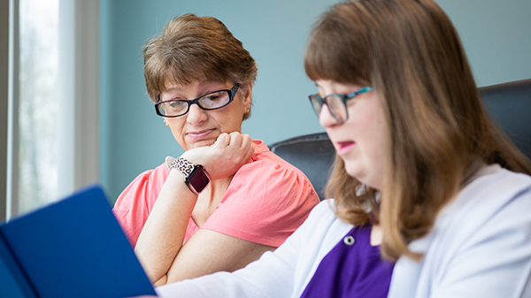 Two women sitting next to each other looking at a notebook