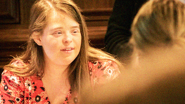 Young woman with Down syndrome listening to someone across the table from her