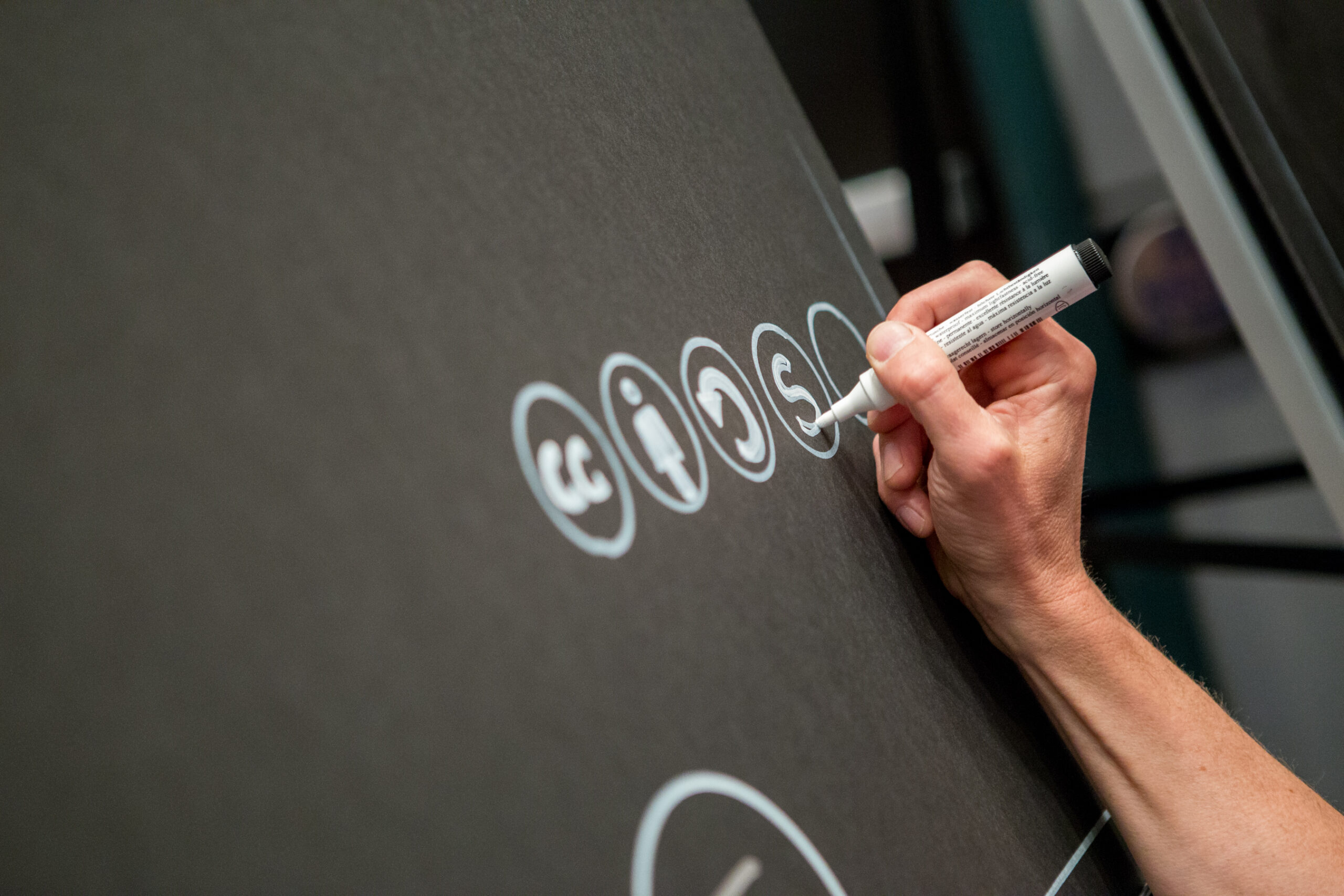 A person writing symbols on a poster board