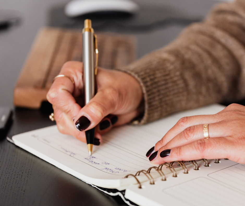 Close-up of a person writing notes in a notebook.