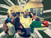 A photo showing staff members sitting around a table and engaging in lively discussion. Some staff use wheelchairs.